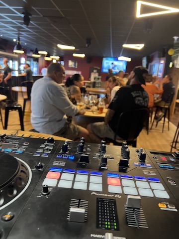 Contrôleur DJ au premier plan d’une soirée dans un bar